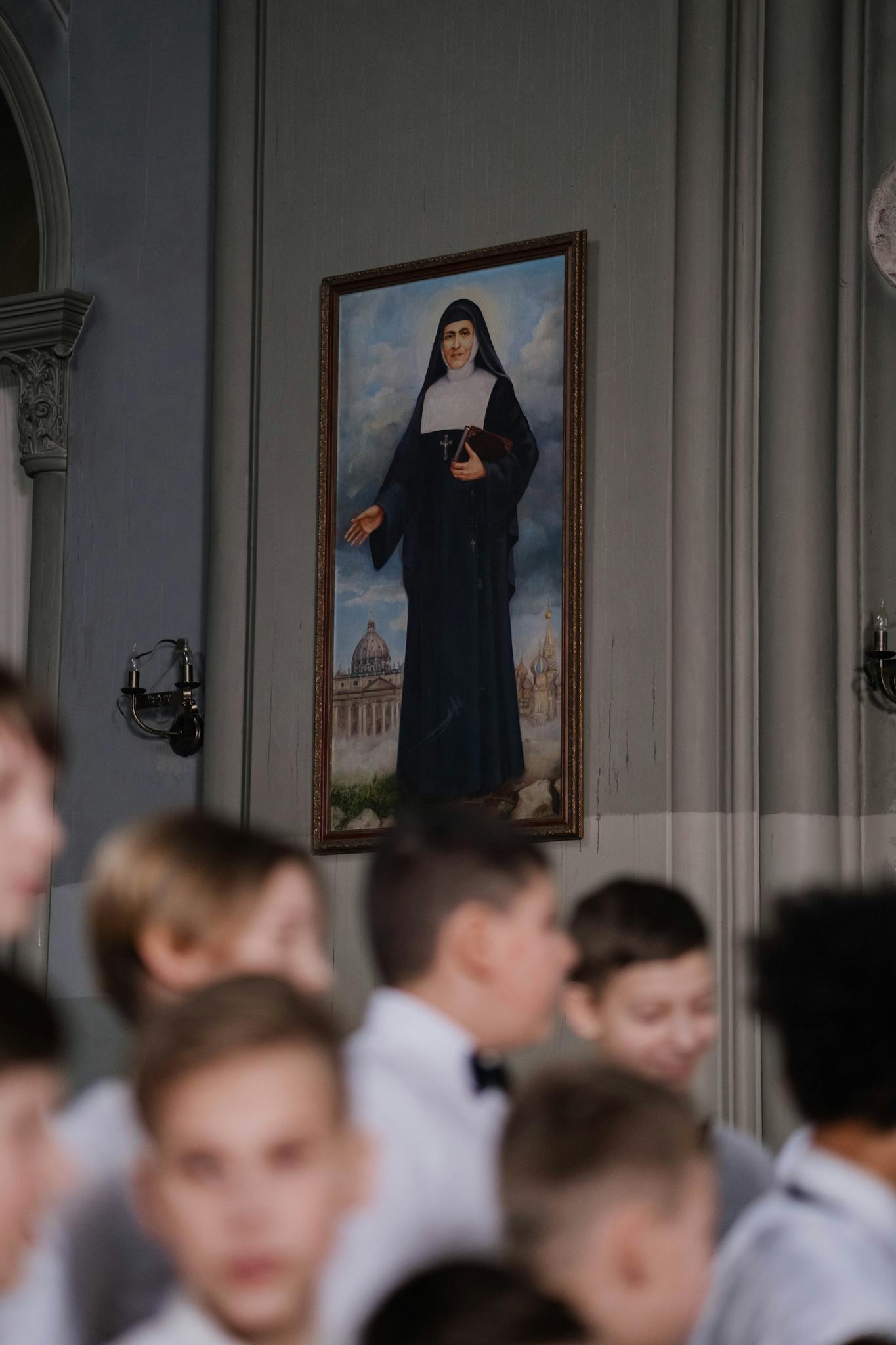 A serene choir with children in front of a nun's painting in a church setting.