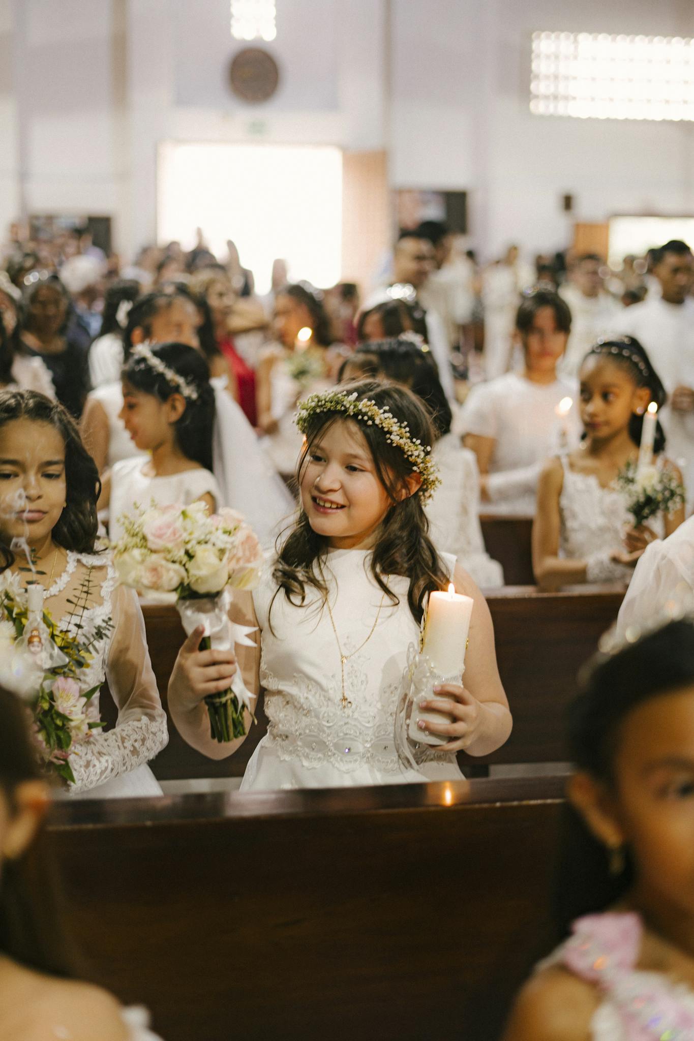 Young girls in white dresses participate in a beautiful First Communion ceremony at a church.